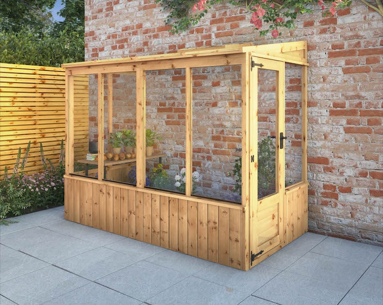 Wooden lean to greenhouse against supporting wall