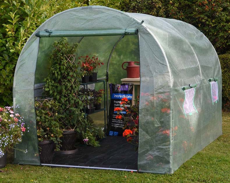 Polytunnel with door open showing fertiliser and potted plants