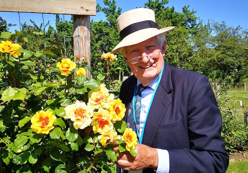 Peter Seabrook standing next to yellow roses