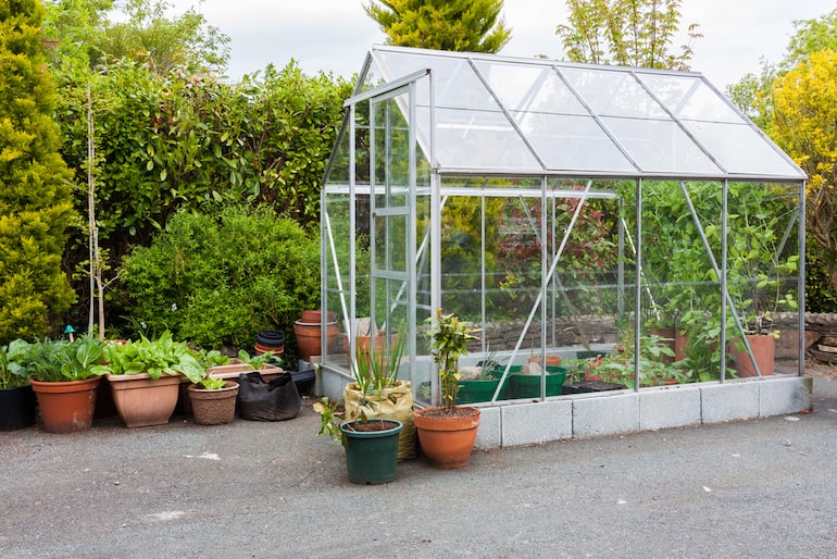 side view of a greenhouse in the garden that has been raised on breeze blocks