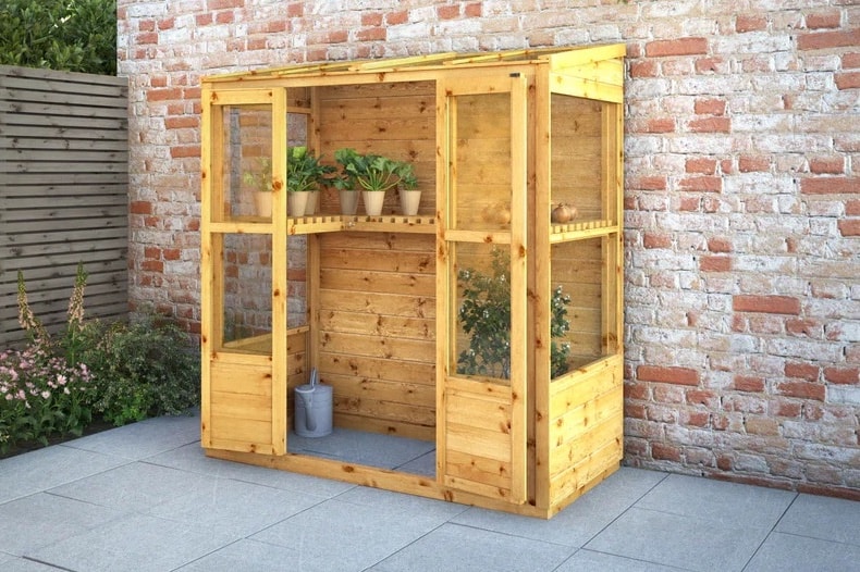 Wooden lean to greenhouse against wall