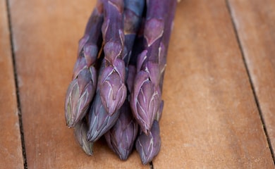 Purple asparagus spears on wooden table