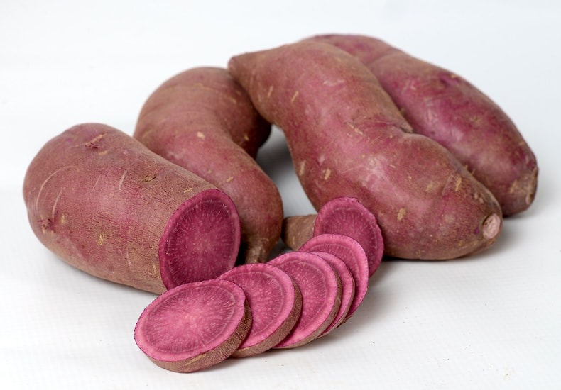 Purple sweet potatoes against white background