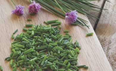 Chives on chopping board with flowers