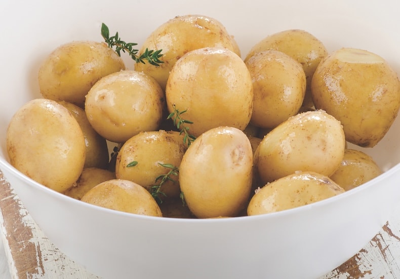 White bowl containing new potatoes